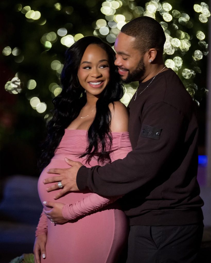 Jasmin Lawrence and Eric Murphy smiling as Eric holds Jasmin's pregnant belly.