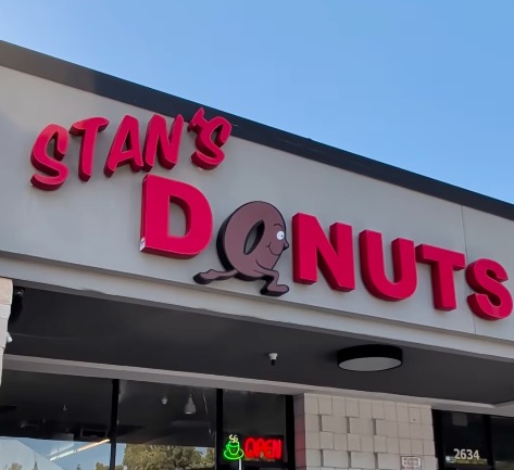 Stan's Donuts sign with a running donut character as the 'O' in Donuts.