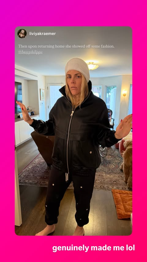 Busy Philipps posing in an oversized black leather jacket, black sweatpants with small white stars, and a white beanie.