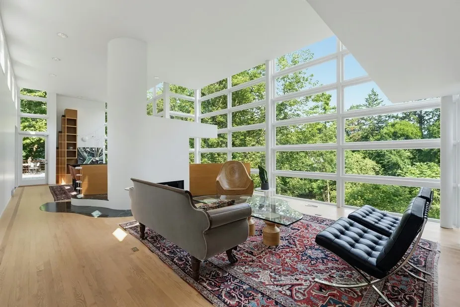 Living room of the upside-down house by architect Kenneth Neumann in Michigan, with floor-to-ceiling windows overlooking a forest.