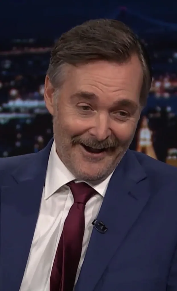 Will Forte laughing with a mustache and beard.