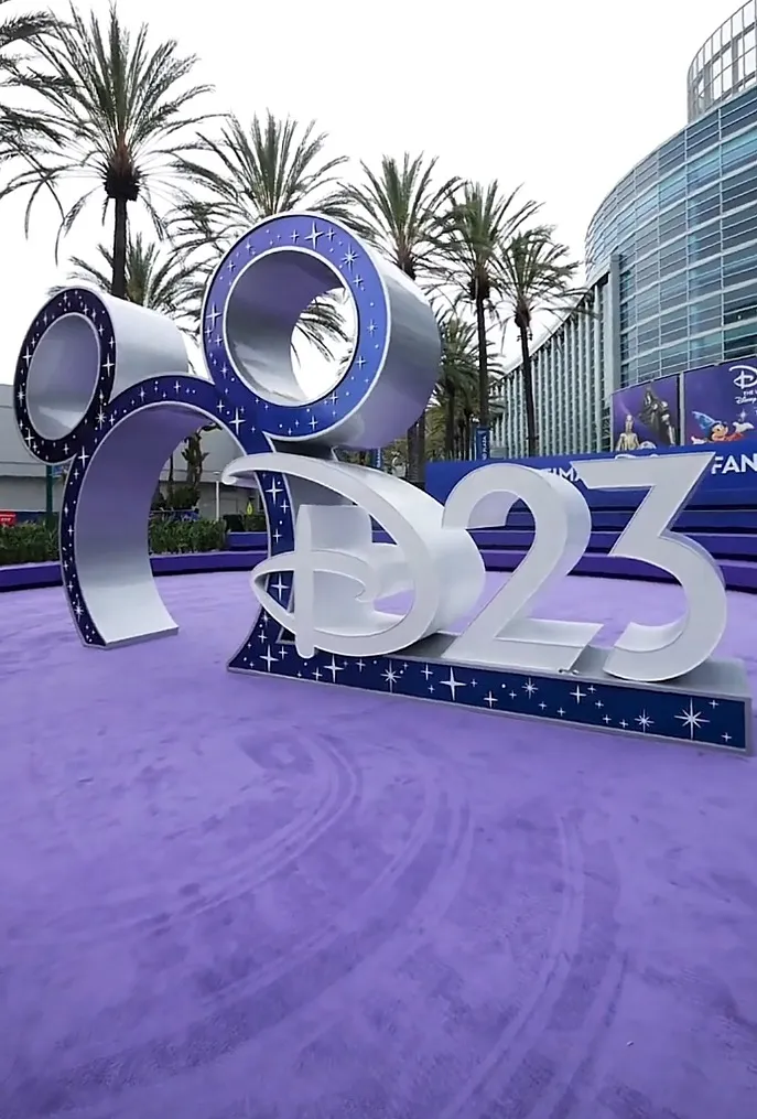 The D23 sign on a purple carpet.