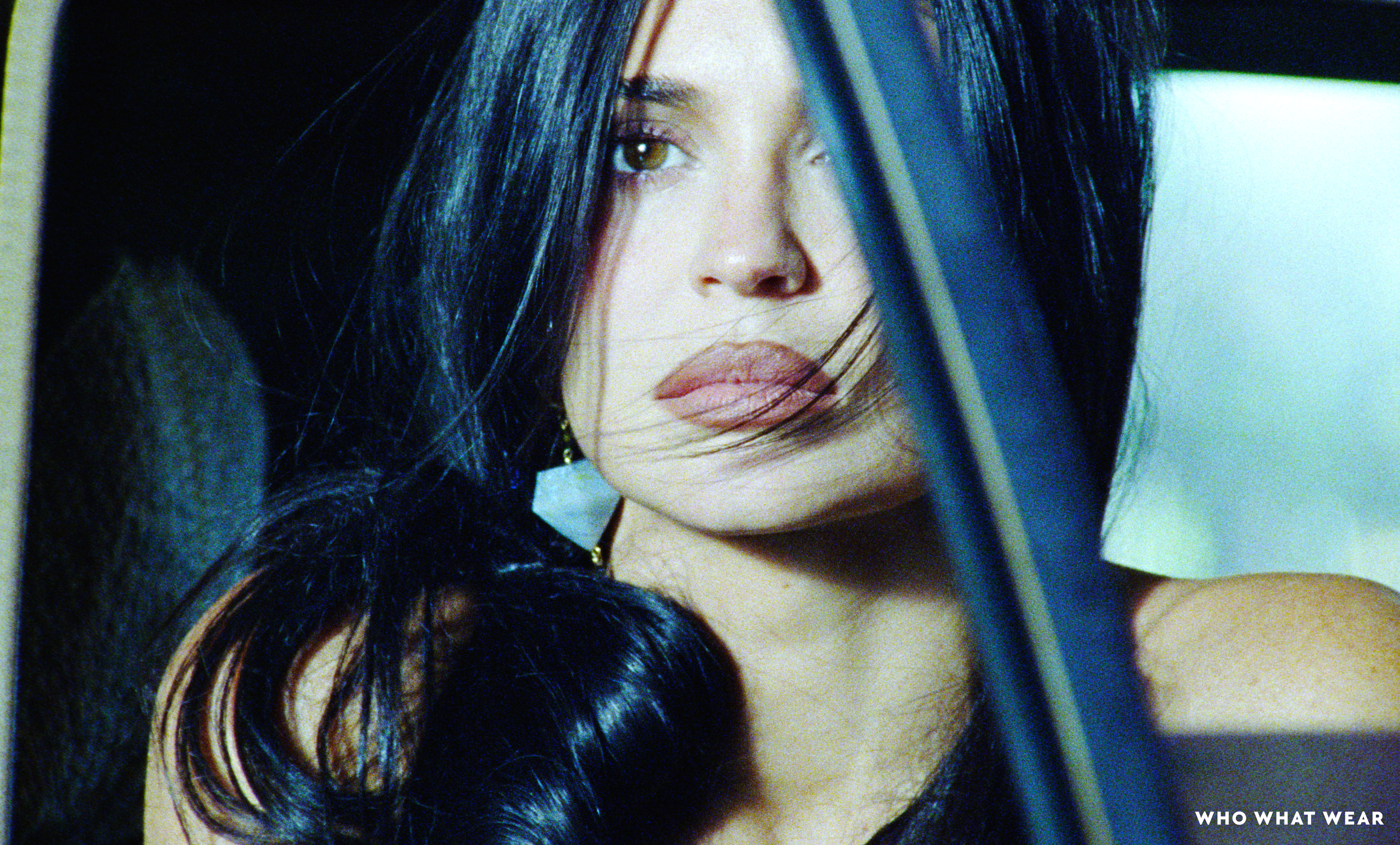 Kylie Jenner looking at the camera with dark hair draped over her face.