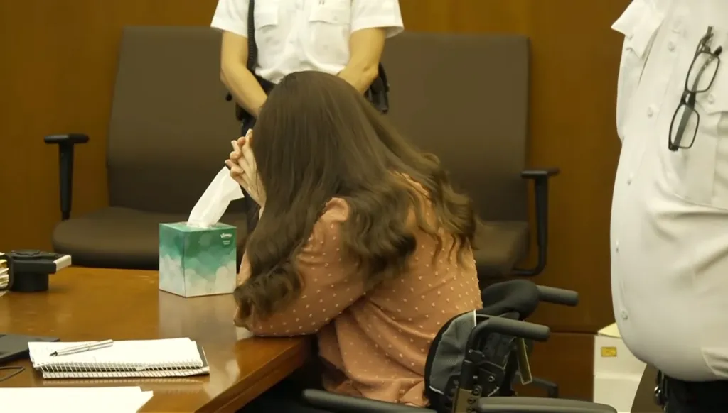 Lindsay Clancy crying in a courtroom, with her head down on a table next to a tissue box.