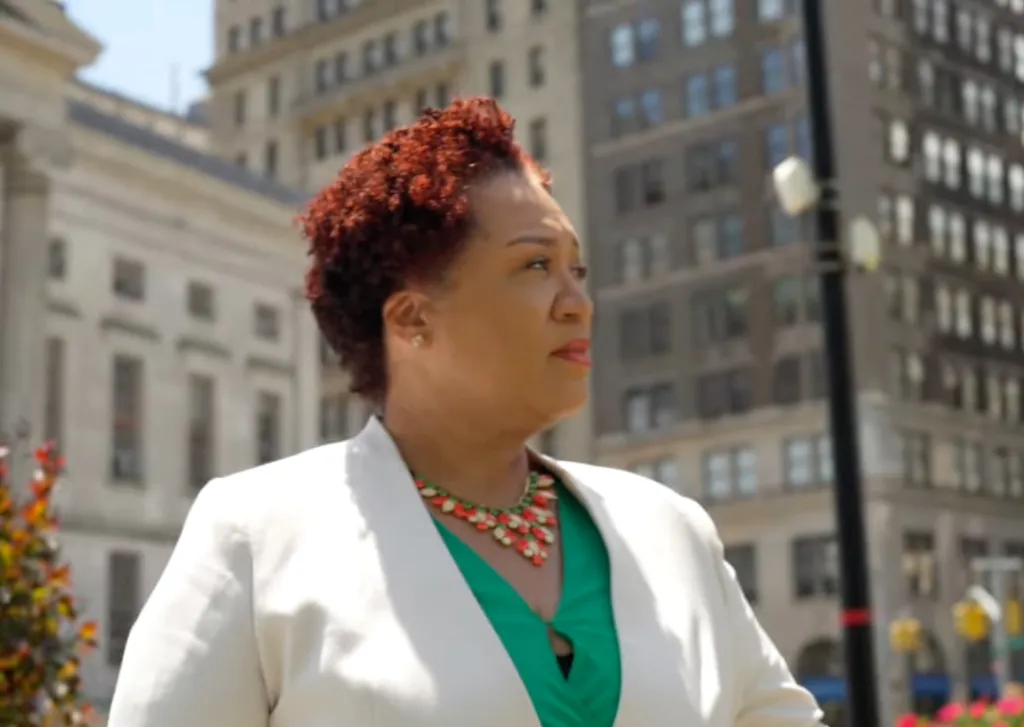 Judge Janice Robinson in a white blazer and green top with a prominent necklace, looking off to the right.