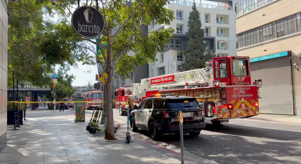 Los Angeles City Fire Department trucks and a police car on a street with yellow caution tape, suggesting an incident.