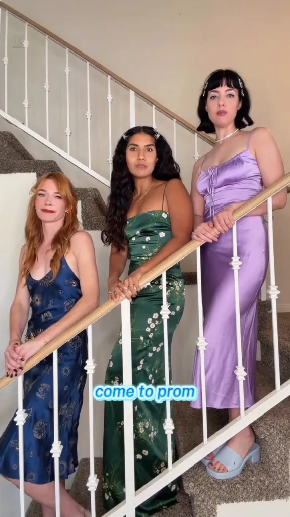 Three women in Y2K-style dresses posing on a staircase for a fundraiser.