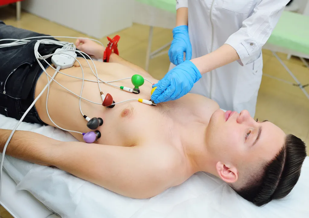 Young male patient receiving an ECG with multi-colored electrodes on his chest.