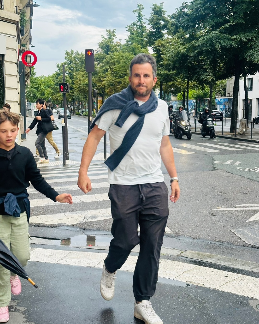 Zach Goldsmith walking across a street, with a child in front of him.