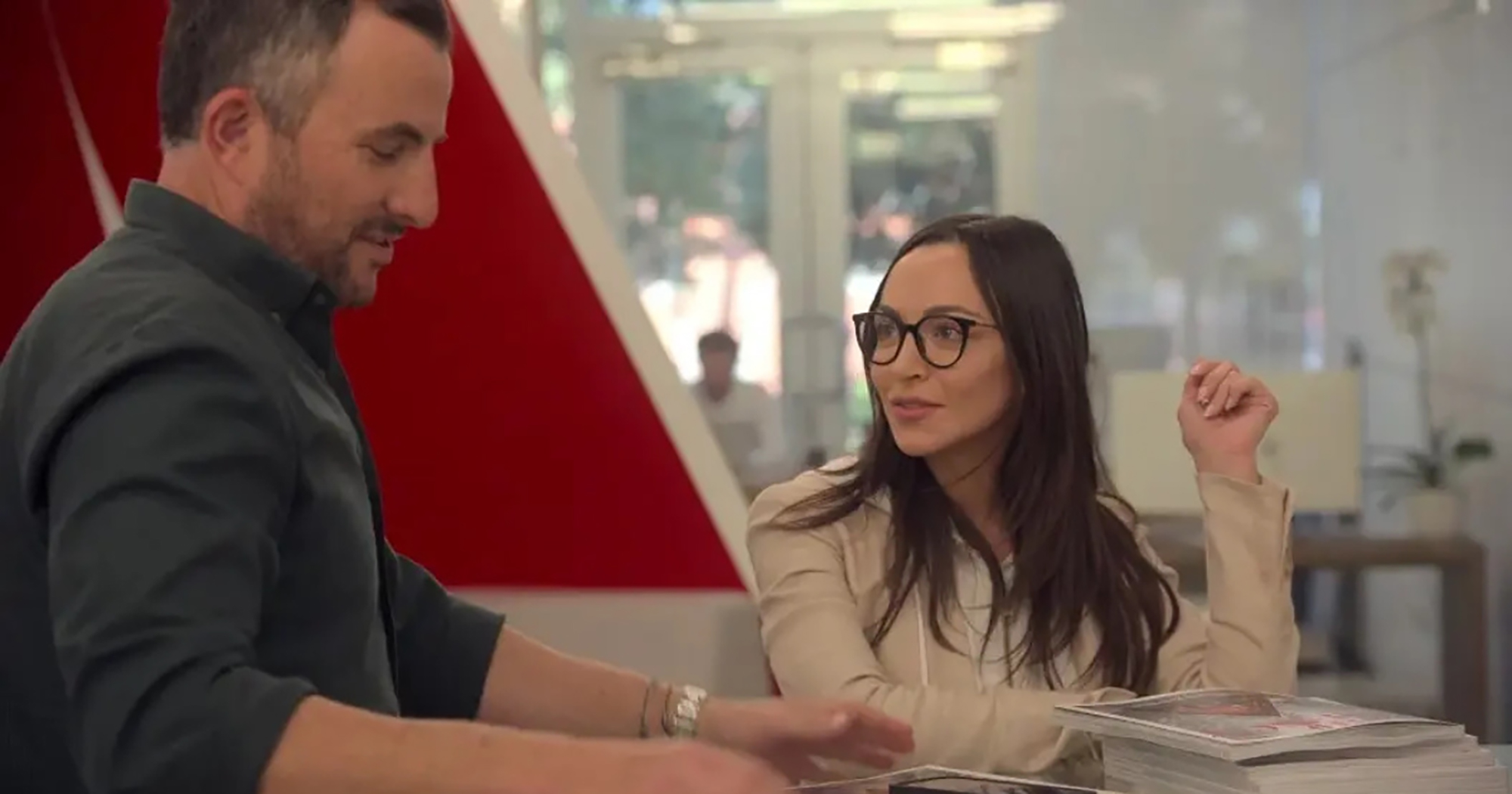 Zach Goldsmith and Farrah Brittany speaking, with Farrah wearing glasses and looking at Zach.