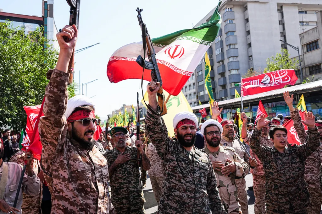 Participants in camouflage raise rifles and an Iranian flag during the Jan-Fada rally in Tehran.
