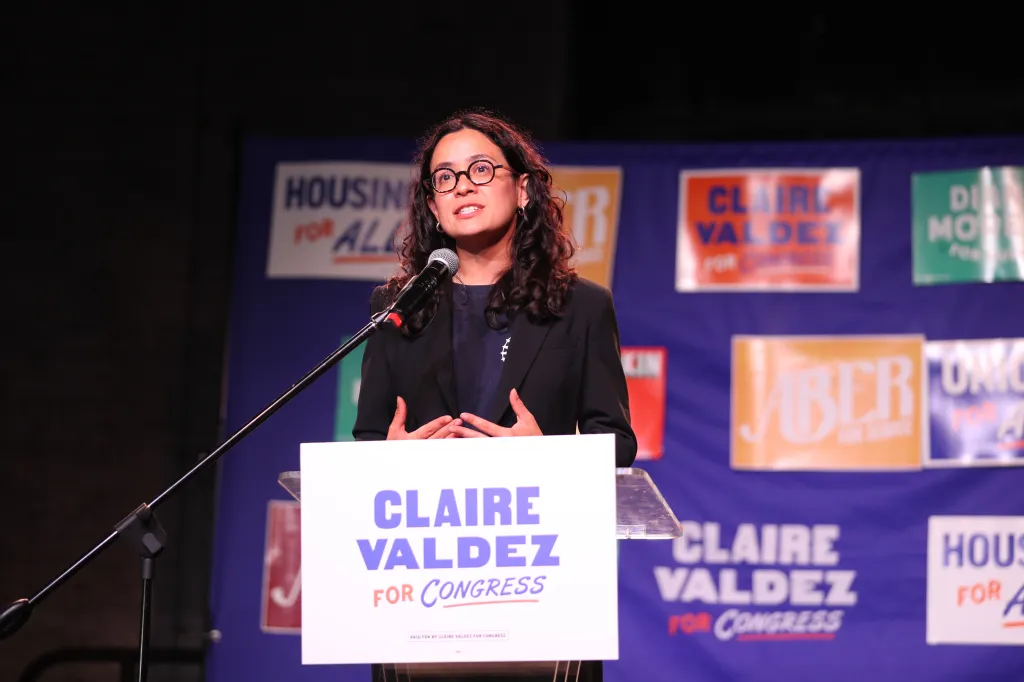 Claire Valdez speaking at a podium with