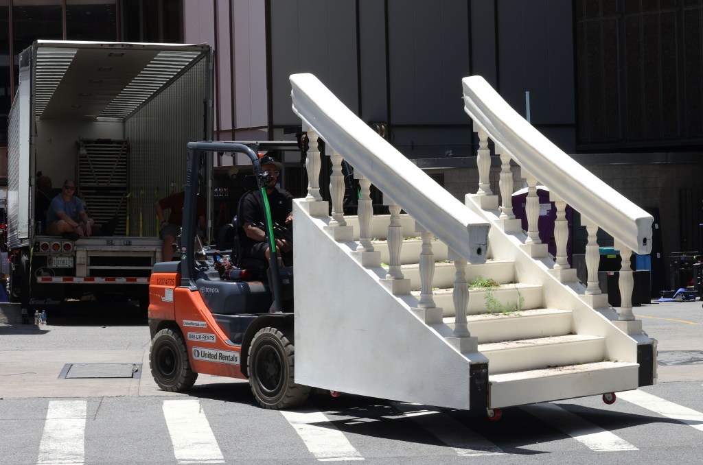 A forklift moves large stage stairs for Taylor Swift and Travis Kelce's wedding setup in Madison Square Garden.