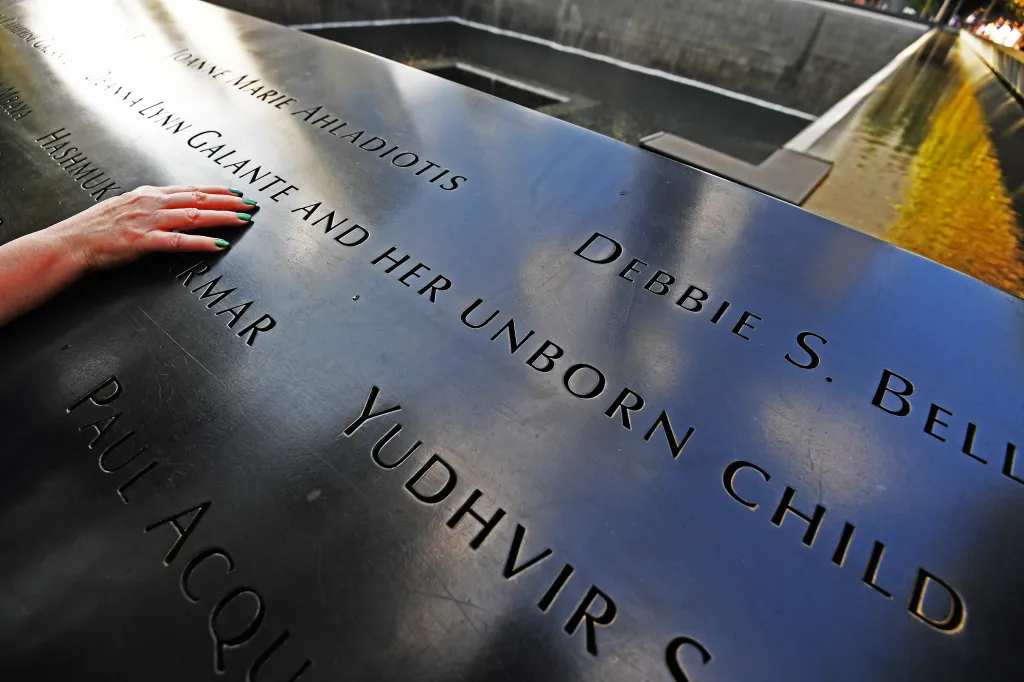Mary Kay Linge's hand rests on the World Trade Center memorial, touching names including
