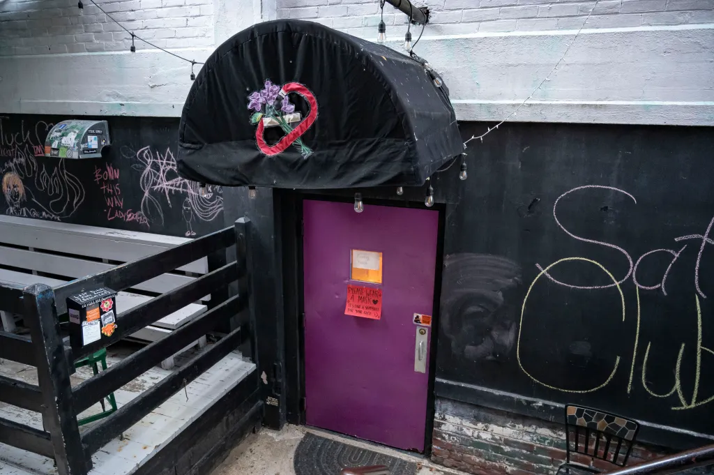 Entrance to the Last Ditch Lesbian Bar with a purple door and a black awning over it.