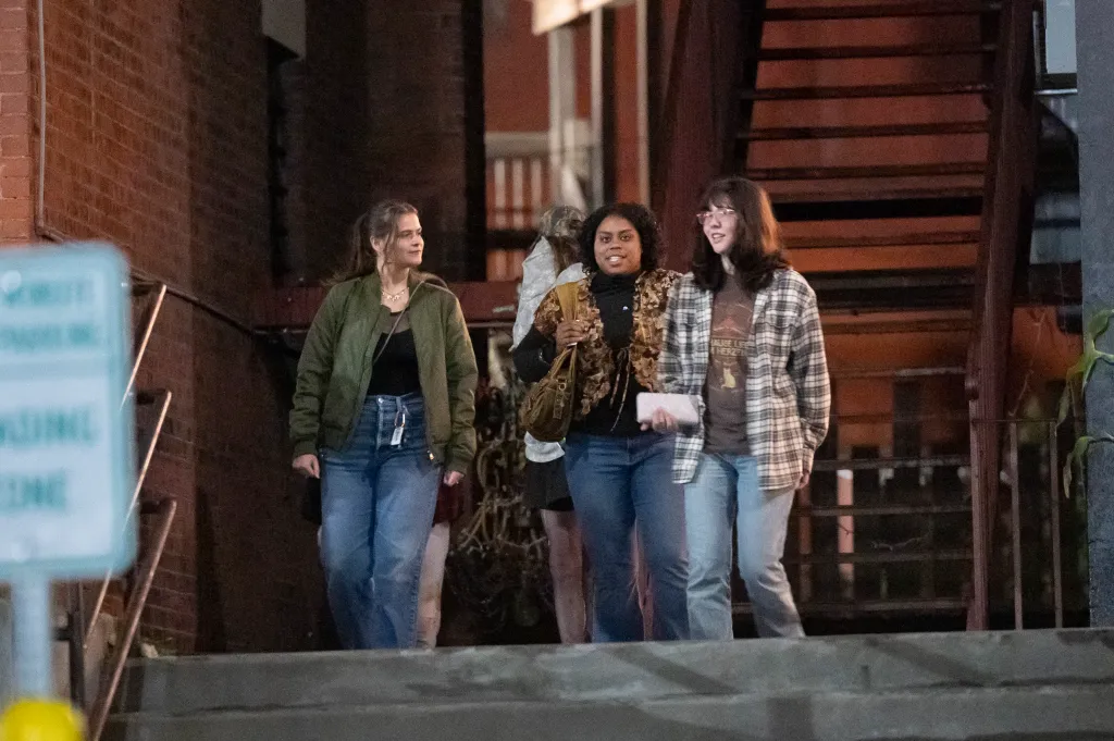 Three women talking together outside the entrance of the Last Ditch Lesbian Bar.
