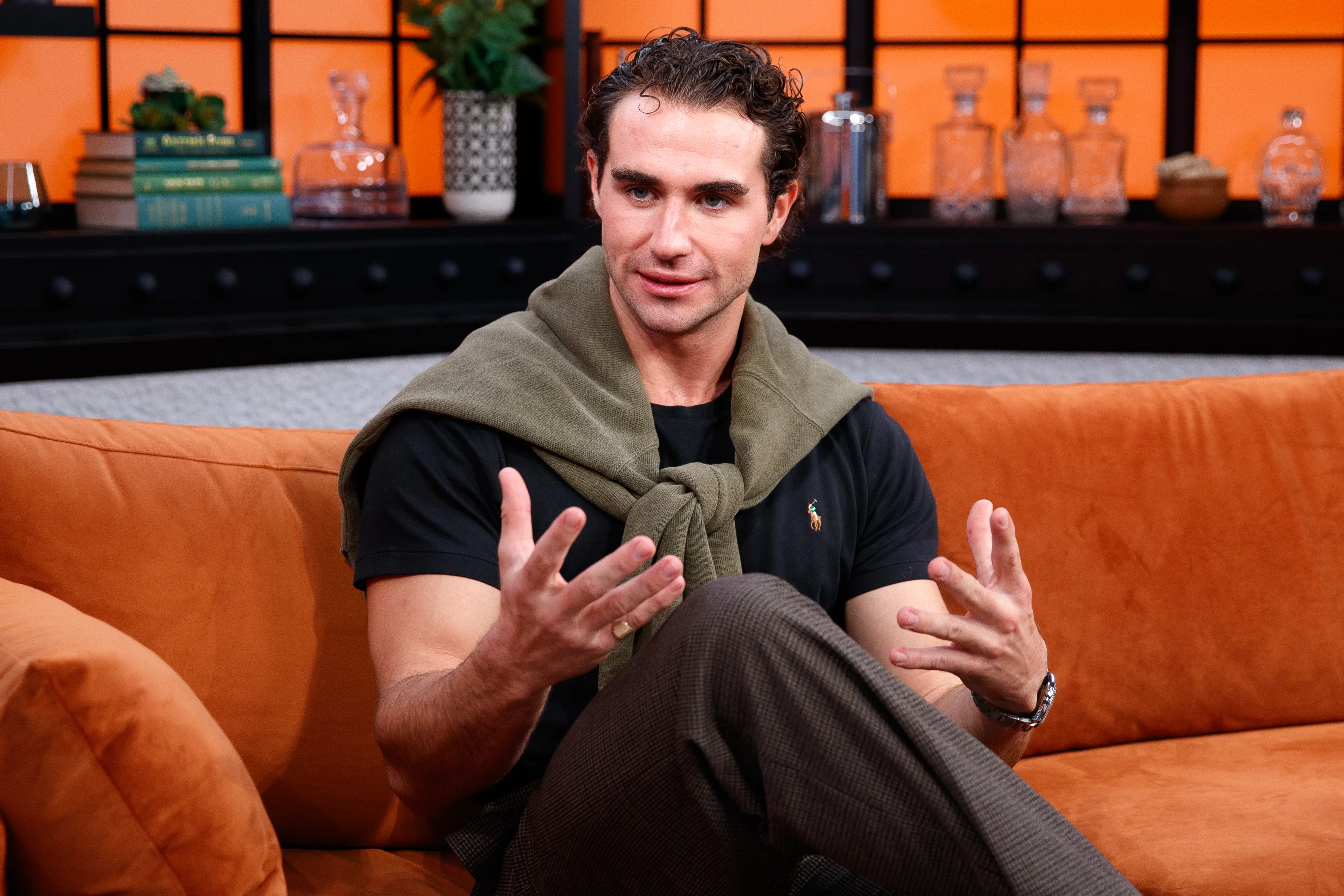 Joe Bradley sitting on an orange couch, speaking during an interview.