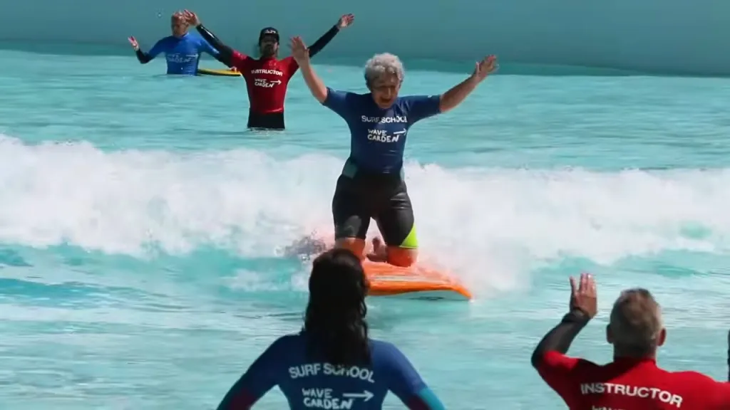 A person surfing on a wave with instructors in a Wavegarden Cove surf school.