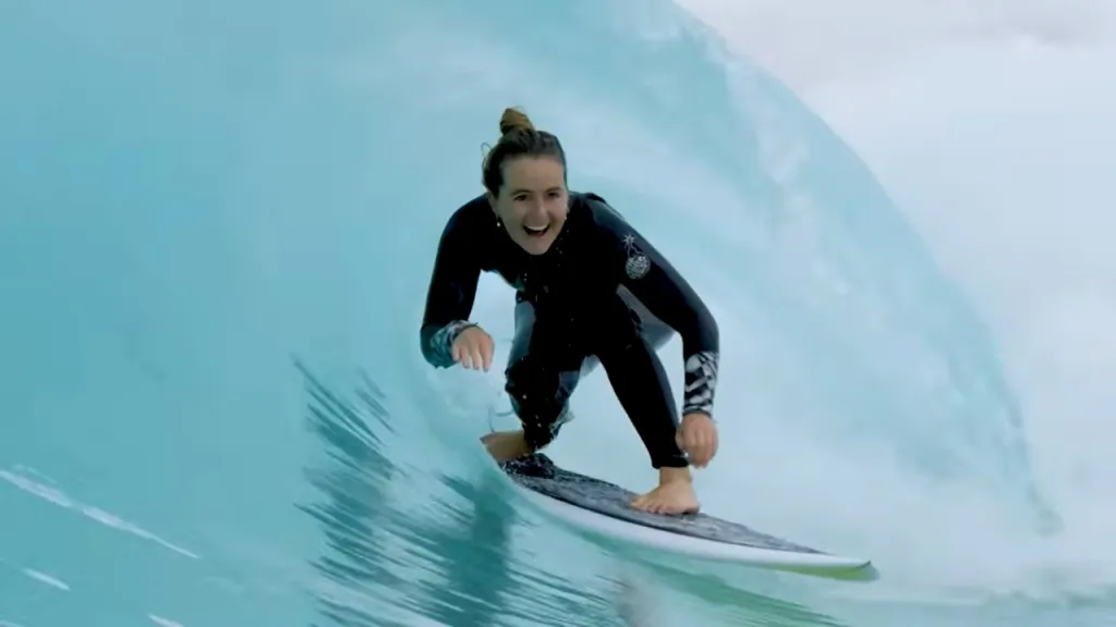 Woman in wetsuit surfing in a wave pool.