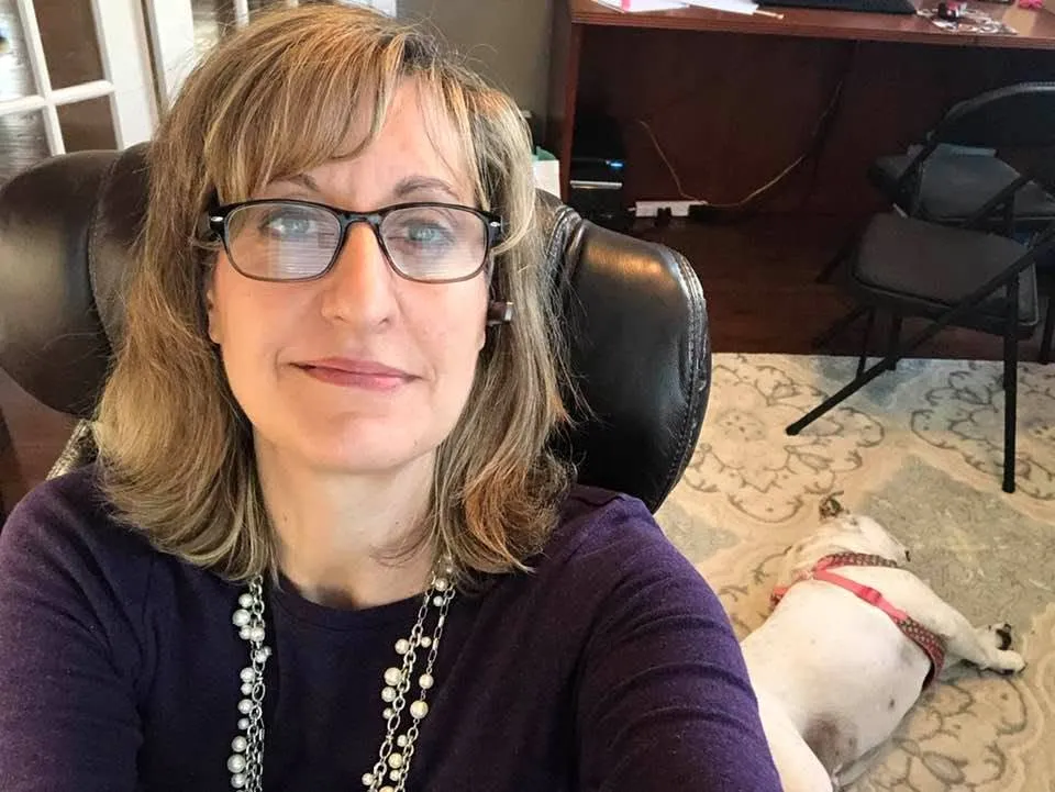 Lisa Arquette Bradford looking into the camera with her dog sleeping on the floor.