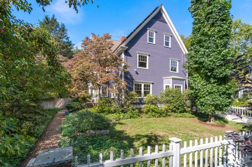 The former home of Julia Child at 103 Irving Street, a large purple house with white trim, a green lawn, and mature trees.