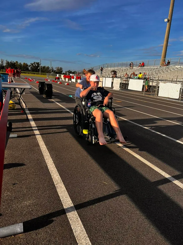 An 11-year-old boy in a wheelchair being pushed by a friend on a track, following a dog attack.