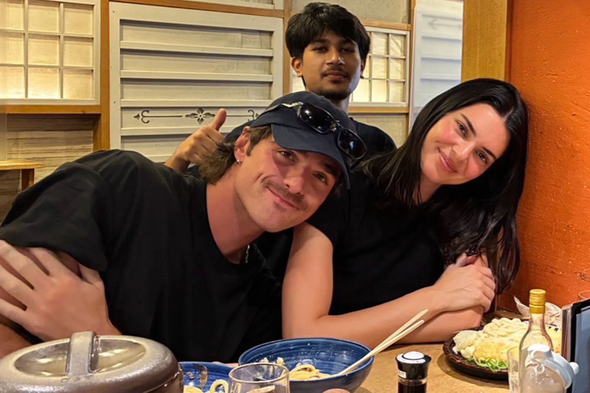 Three people, a woman and two men, smiling at the camera at a table with food.