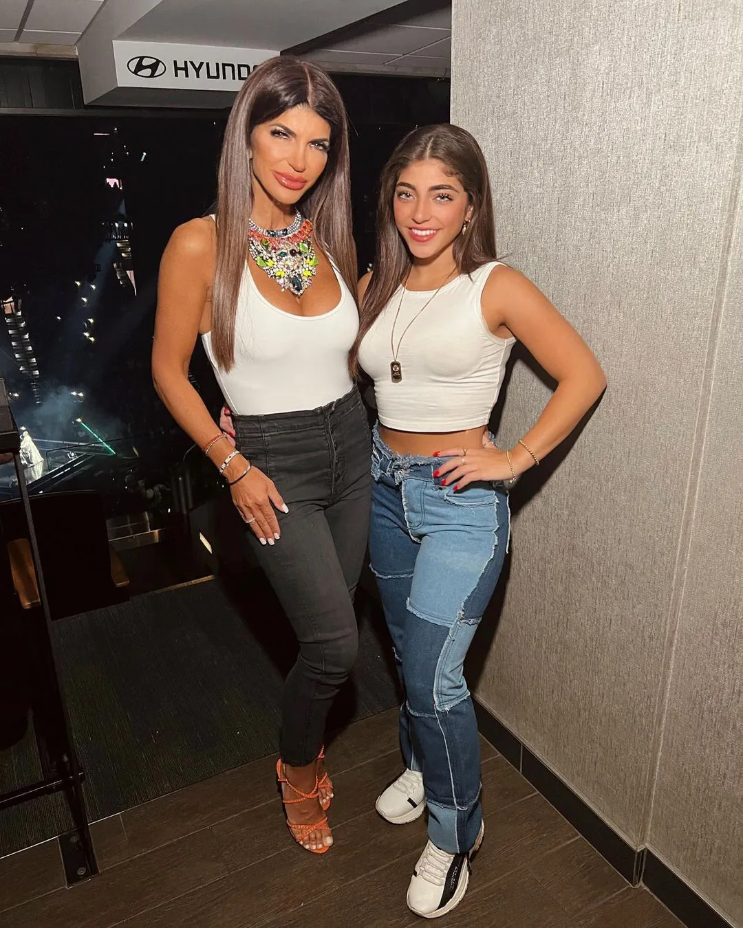 Two women posing together, with a Hyundai logo visible in the background.