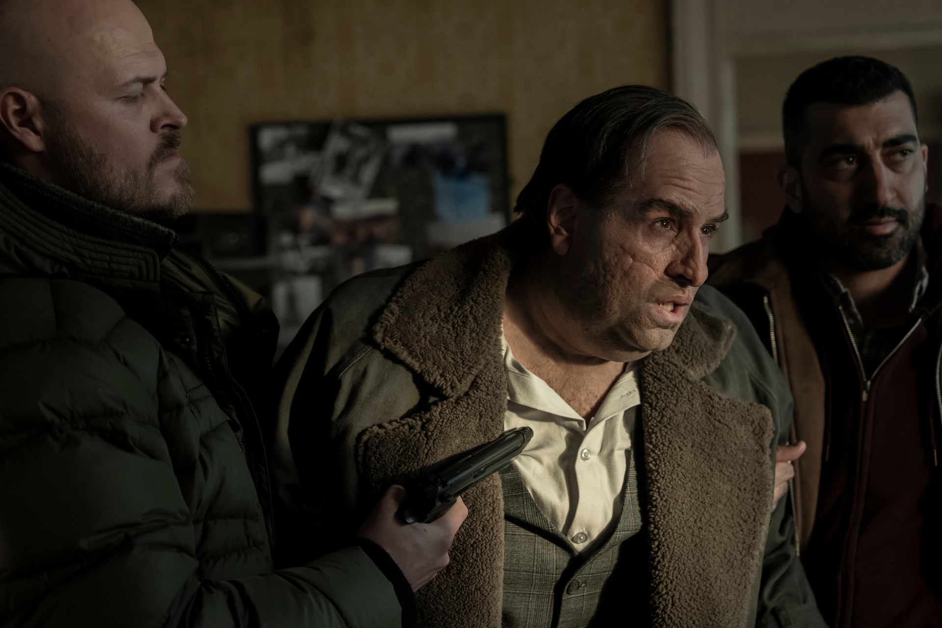 Colin Farrell as Oz Cobb (The Penguin) looking distressed with two men, one holding a gun to his chest.