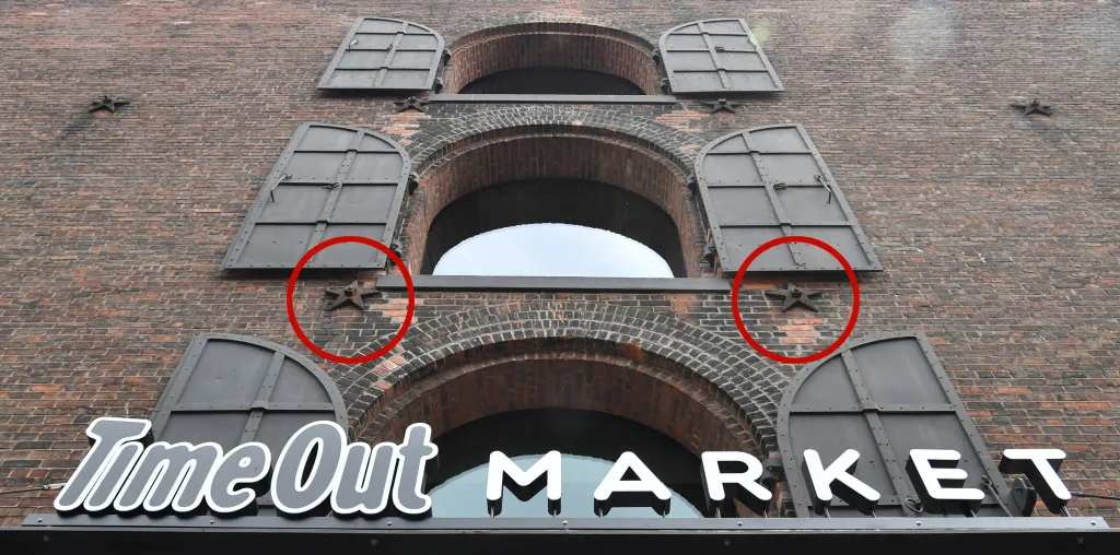 A brick building with arched windows, dark metal shutters, and the