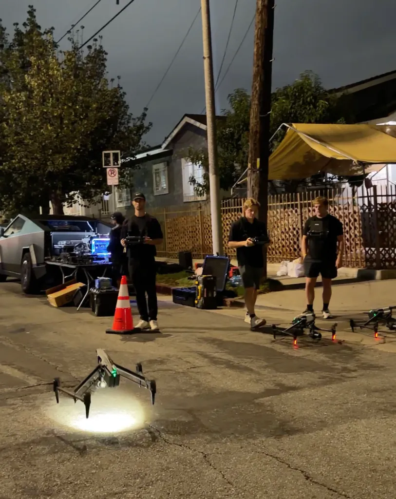 People operating drones at night, with a Cybertruck in the background.