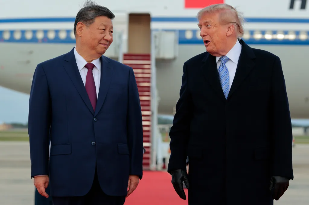 Donald Trump and Xi Jinping walking on a red carpet with an airplane in the background.