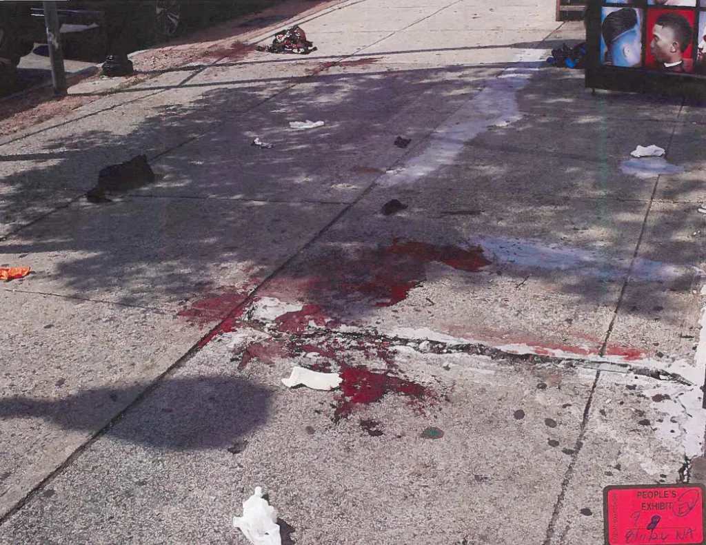 Concrete sidewalk stained with blood, with scattered debris and a