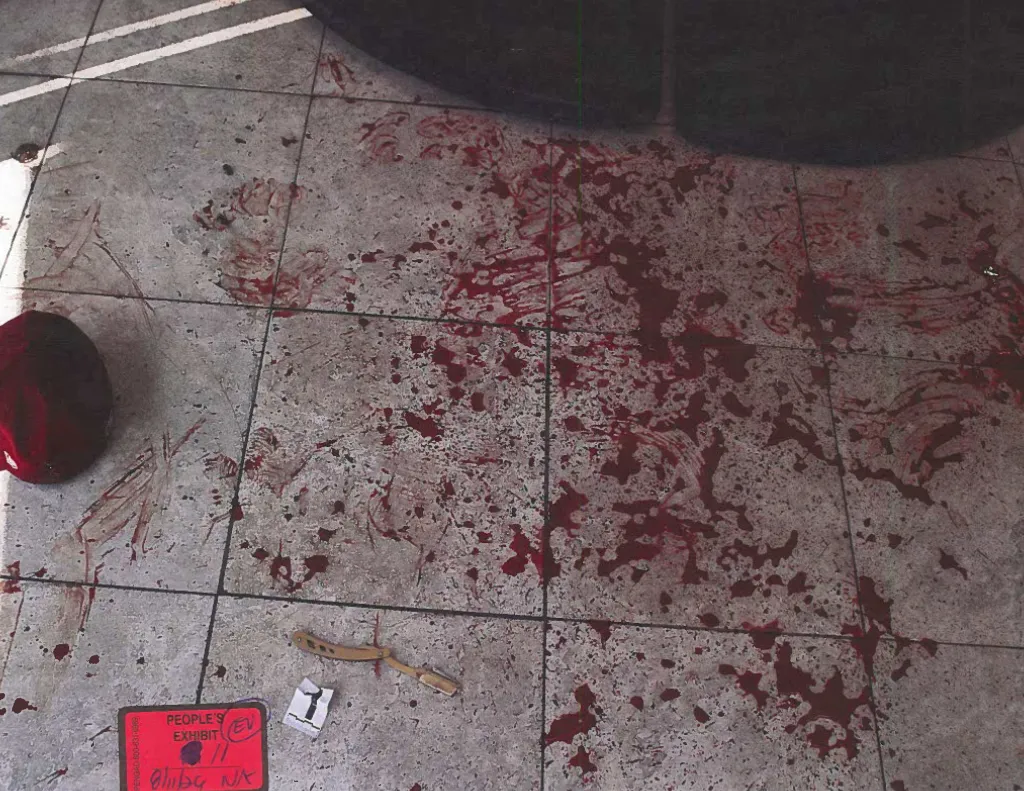 A bloody tiled floor with a red container, a straight razor, and two evidence markers.