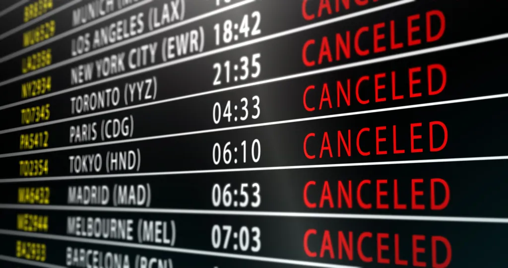 An airport departure board displaying multiple flights with bold red 