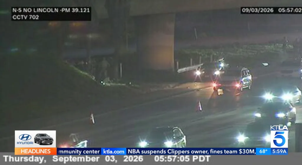 CCTV footage of a freeway crash site at night with emergency vehicles and flashing lights.