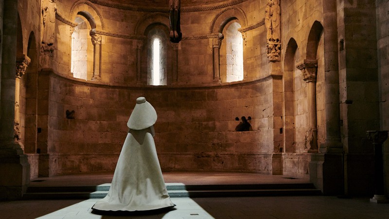 A white dress and white hood on a mannequin in a castle-like space
