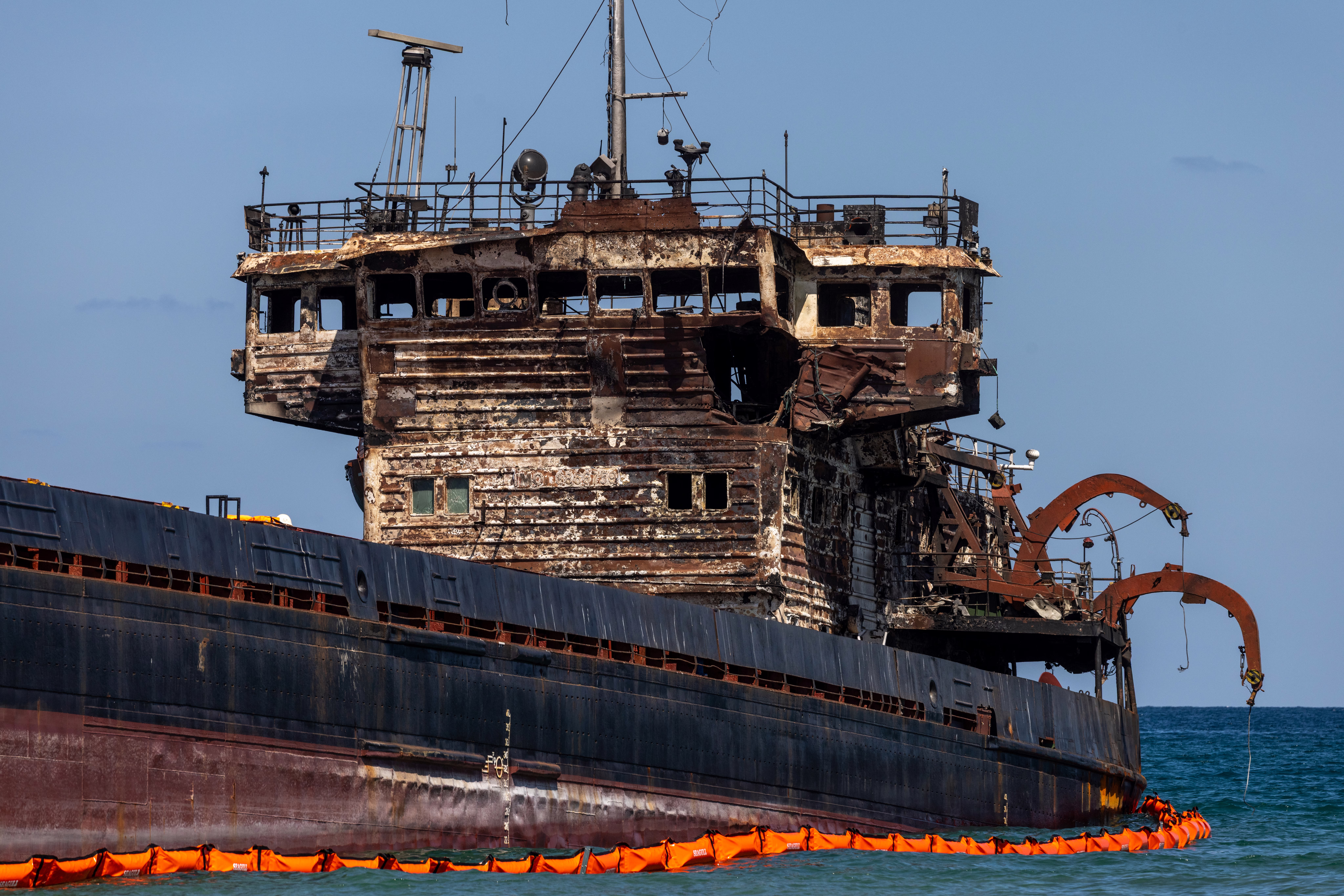 An abandoned, heavily-damaged cargo ship, listing a bit