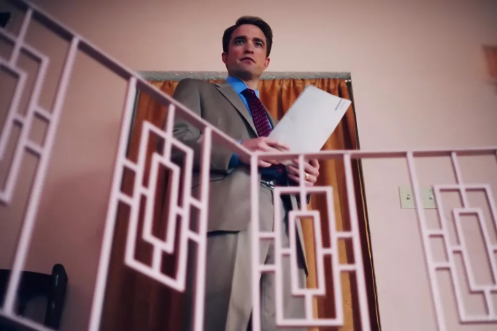 A man in a suit looks up from a landing.