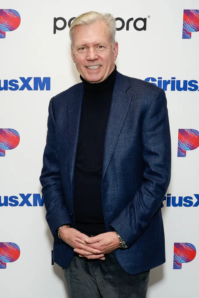 Chris Hansen smiles in a blue blazer and black turtleneck.