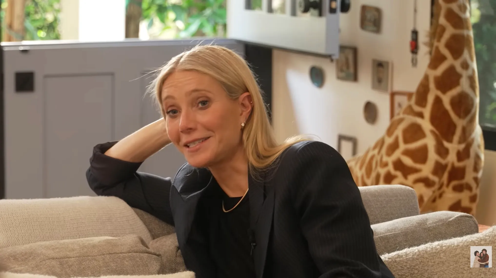 Gwyneth Paltrow sits on a couch, talking.