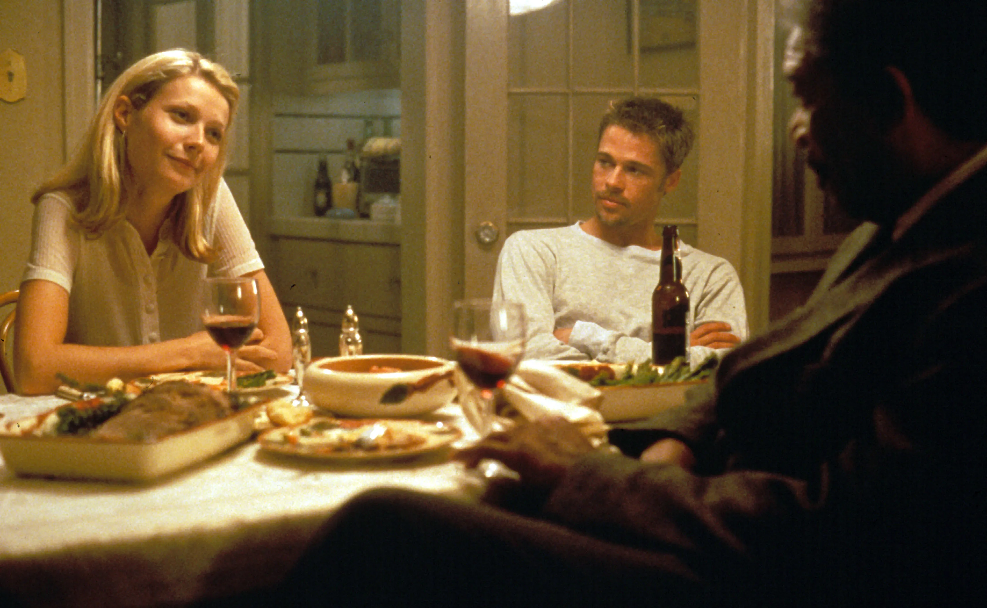 Gwyneth Paltrow, Brad Pitt, and Morgan Freeman seated at a dinner table in a film still from 