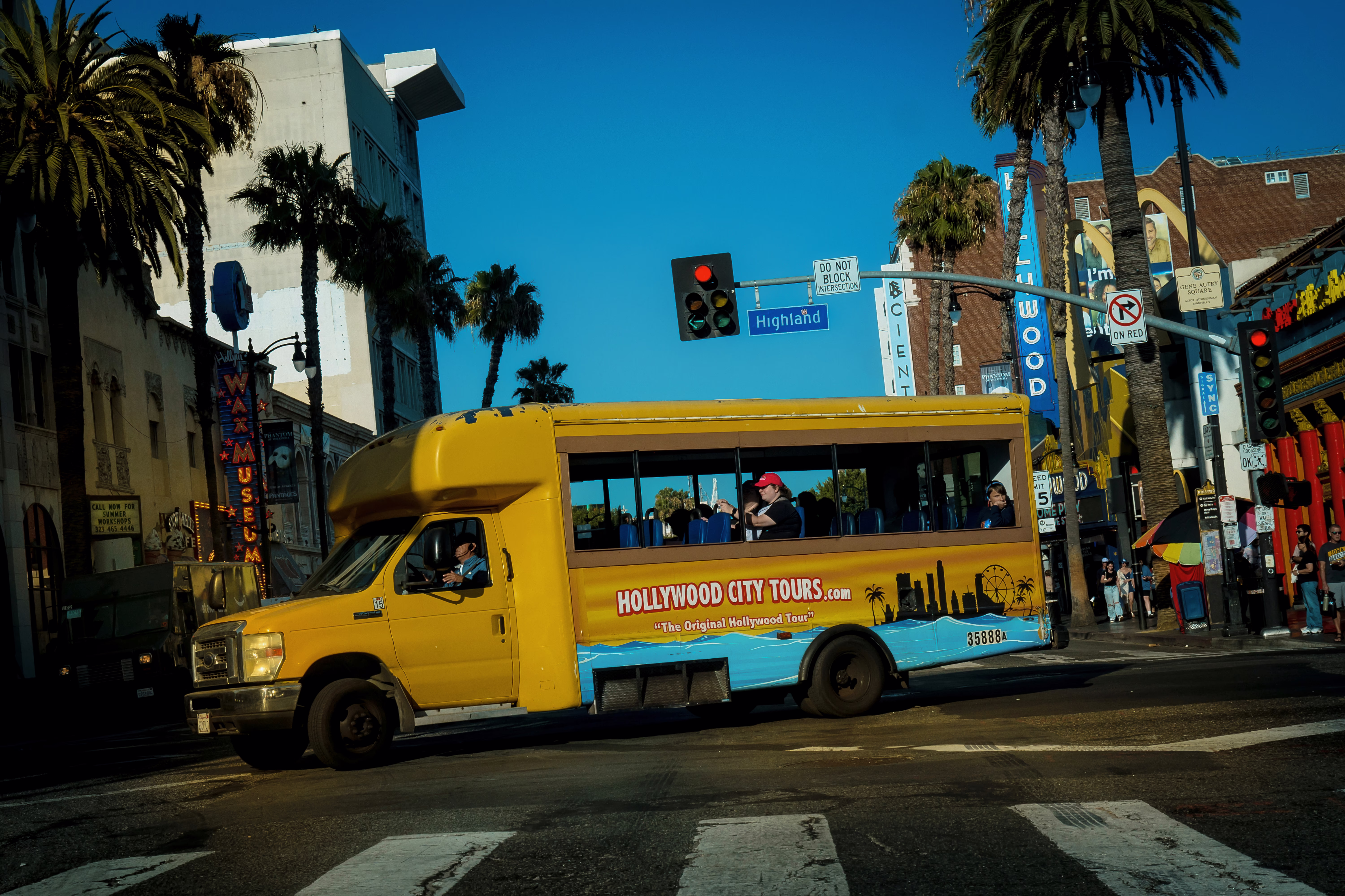 photo of intersection at Highland with bright yellow Hollywood City Tours bus 