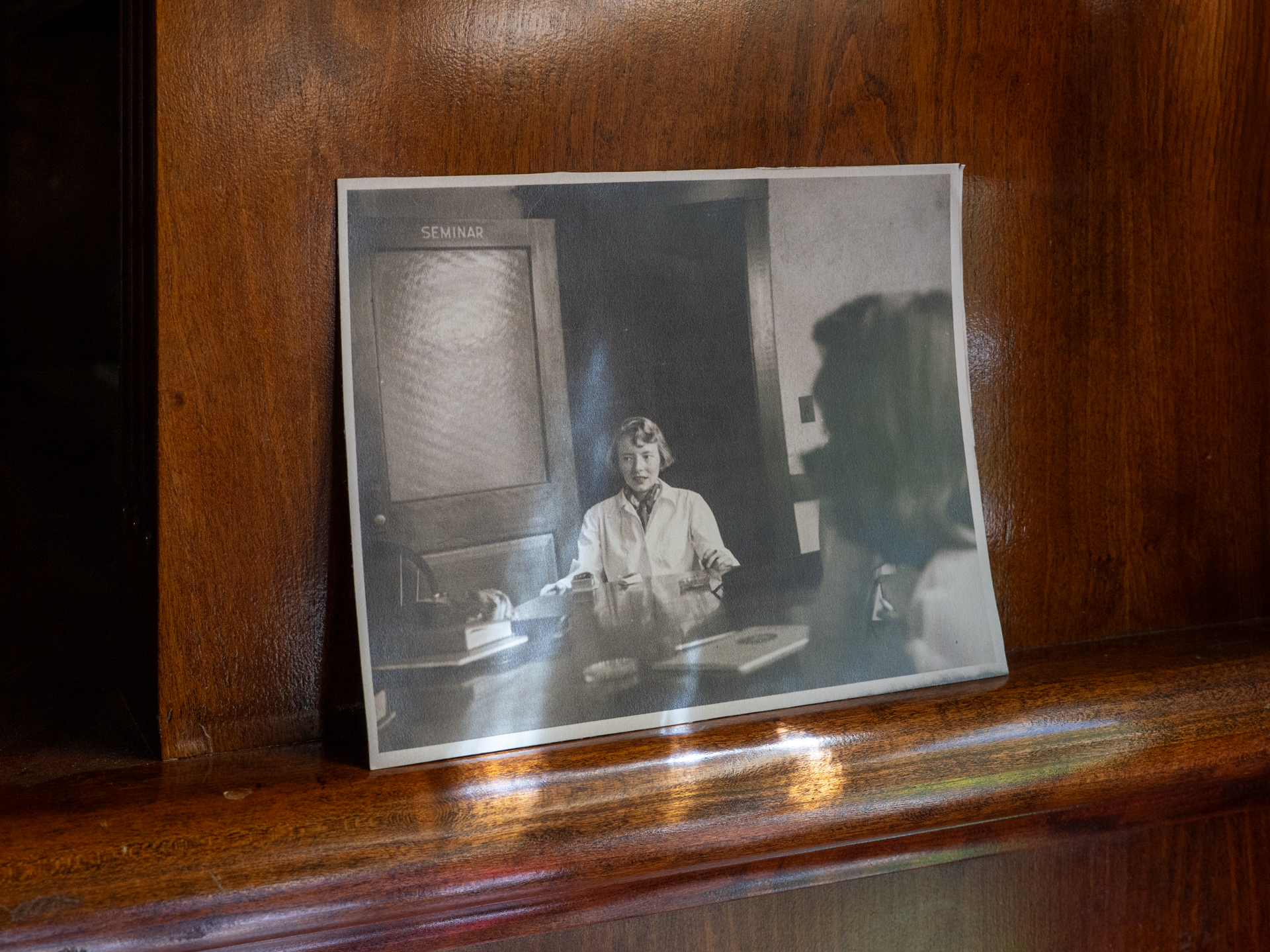 photo of black-and-white printed photo of woman sitting at classroom table