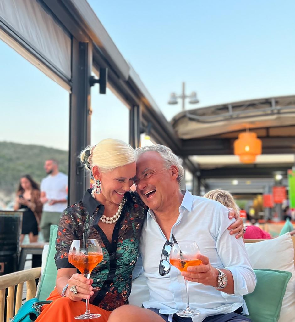 Silvio Scaglia and Michelle-Marie Heinemann embracing and laughing while holding drinks.