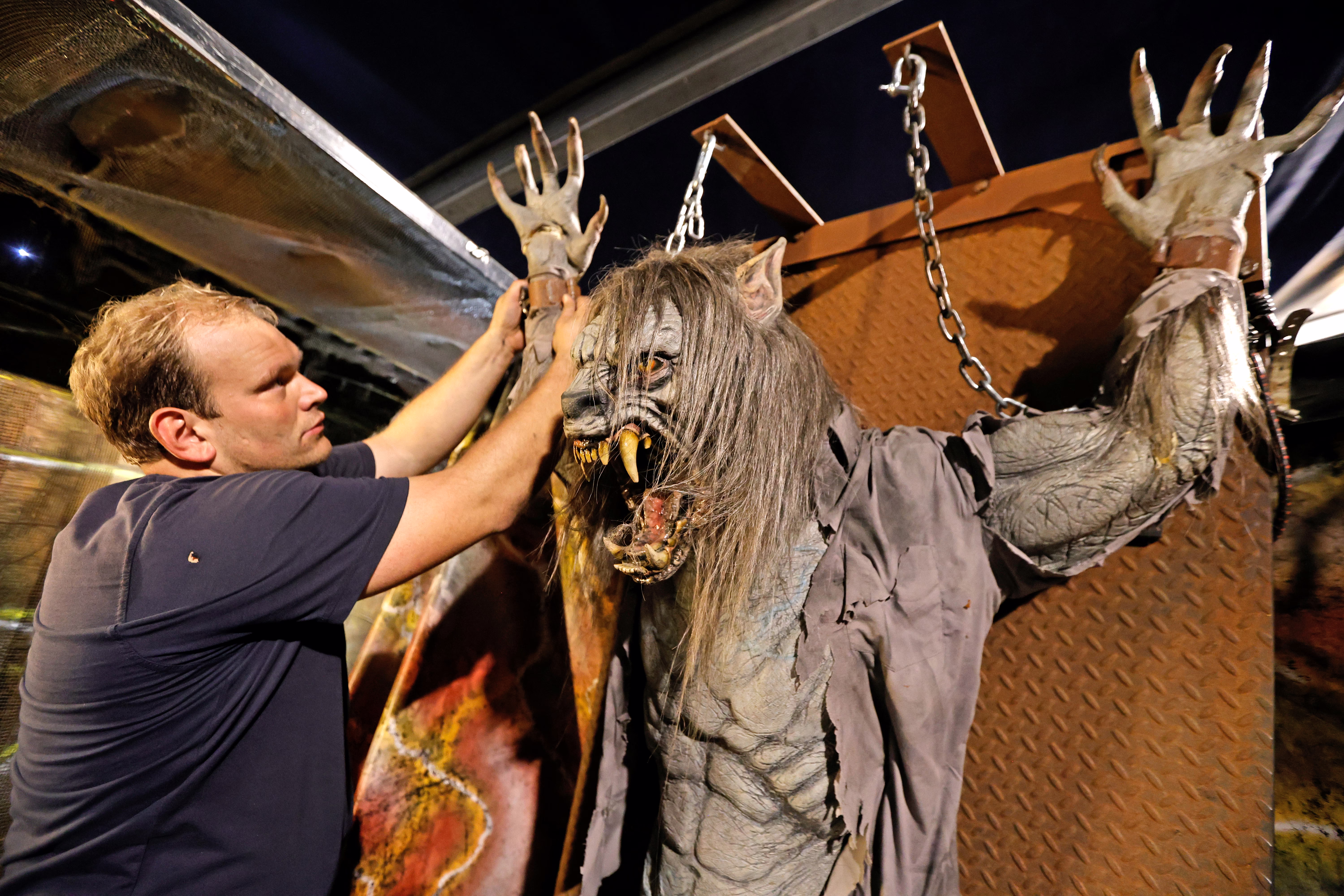 A person sets up a frightening werewolf figure for a haunted house experience.