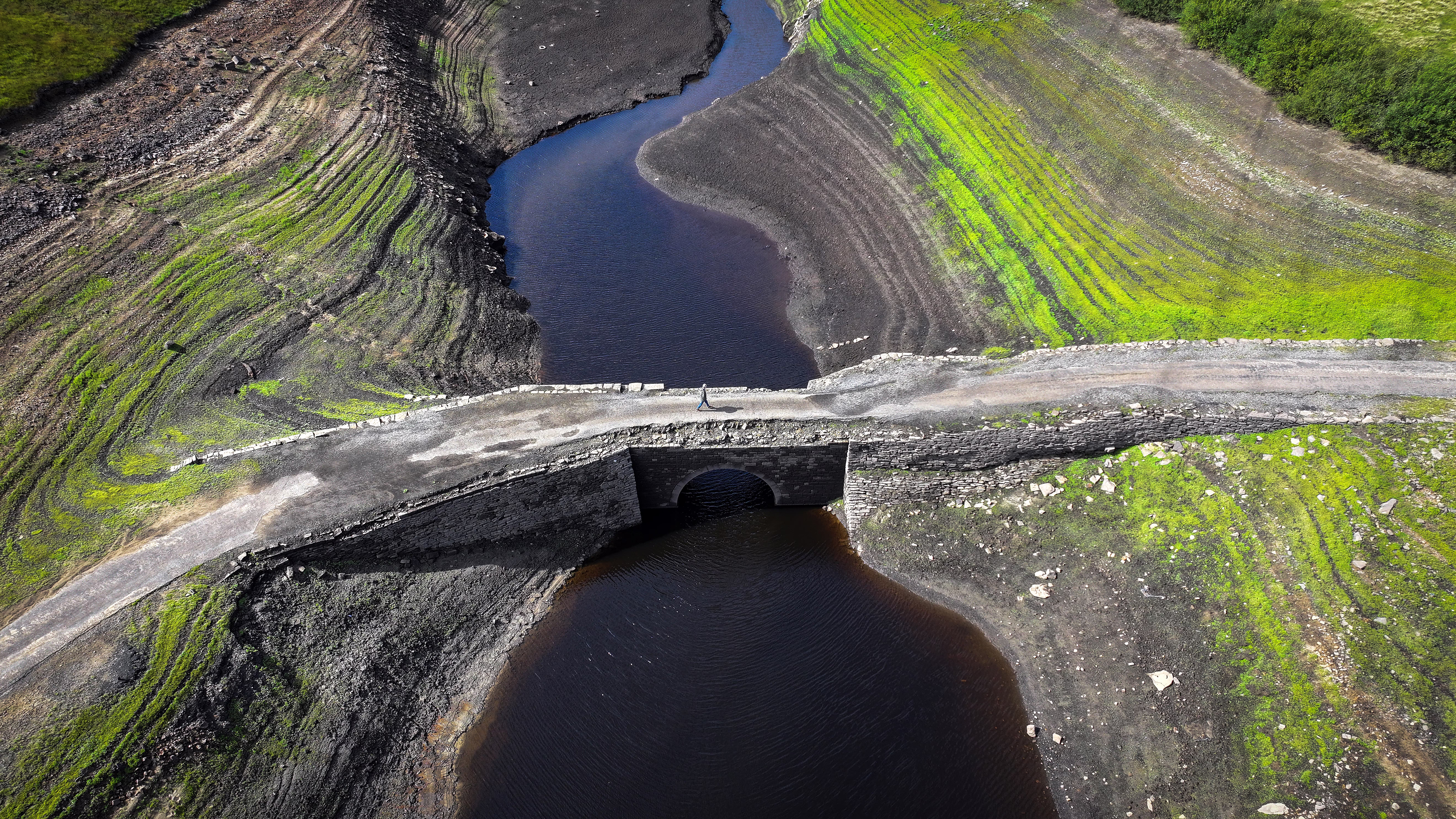 An aerial view of an ancient bridge over a drying reservoir.