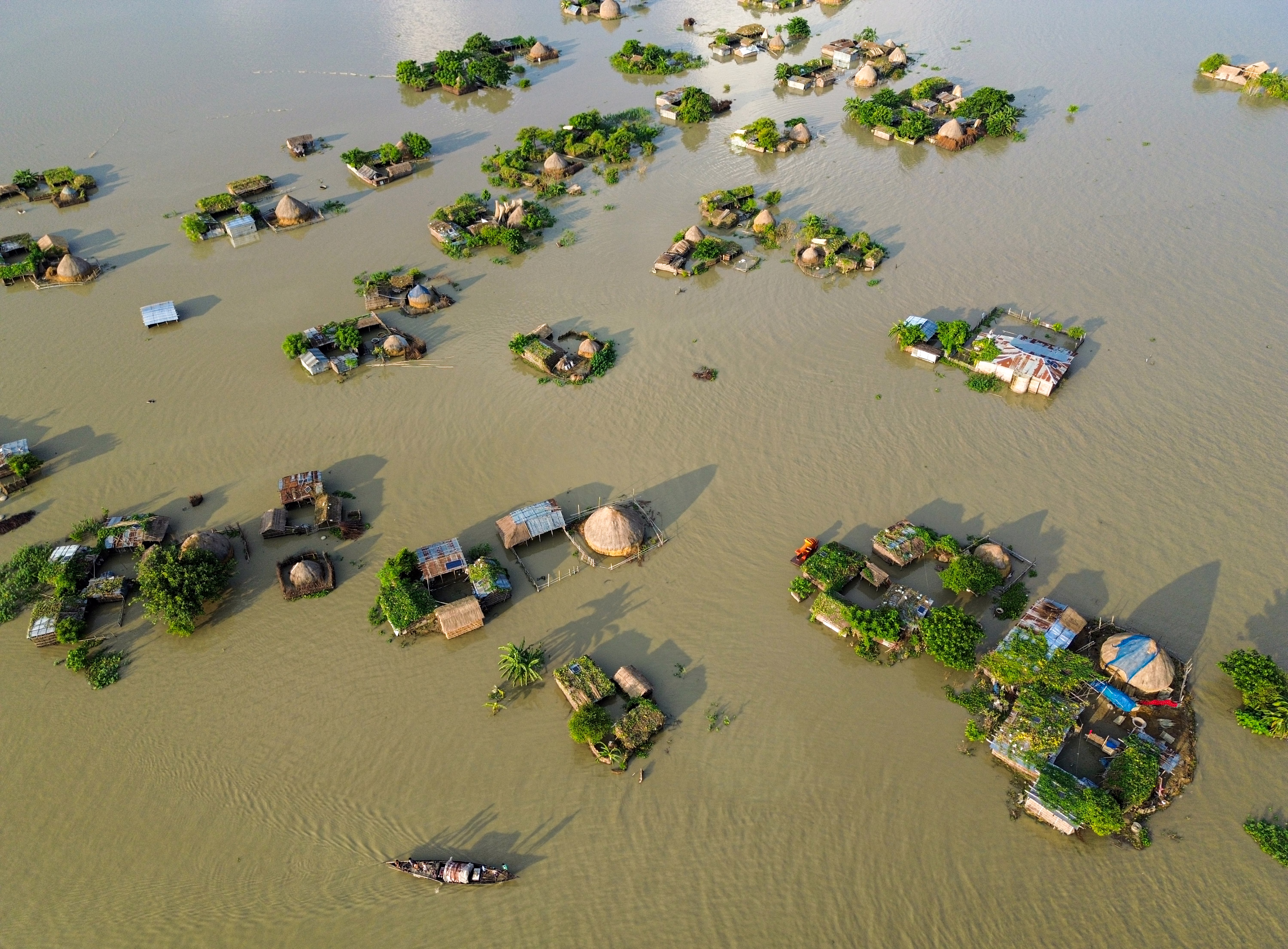 An aerial view shows homes and farmland surrounded by floodwater.