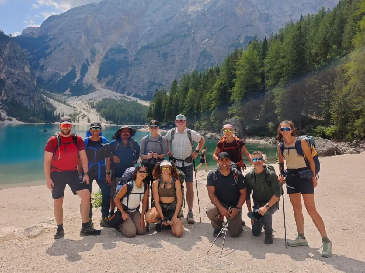 A group of hikers take a photo with a lake in the background.