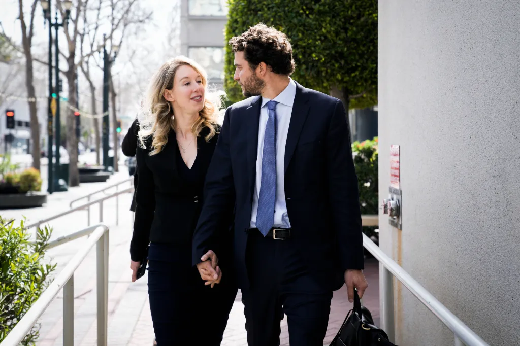 Elizabeth Holmes and Billy Evans walking hand-in-hand outside the Robert F. Peckham U.S. Courthouse.